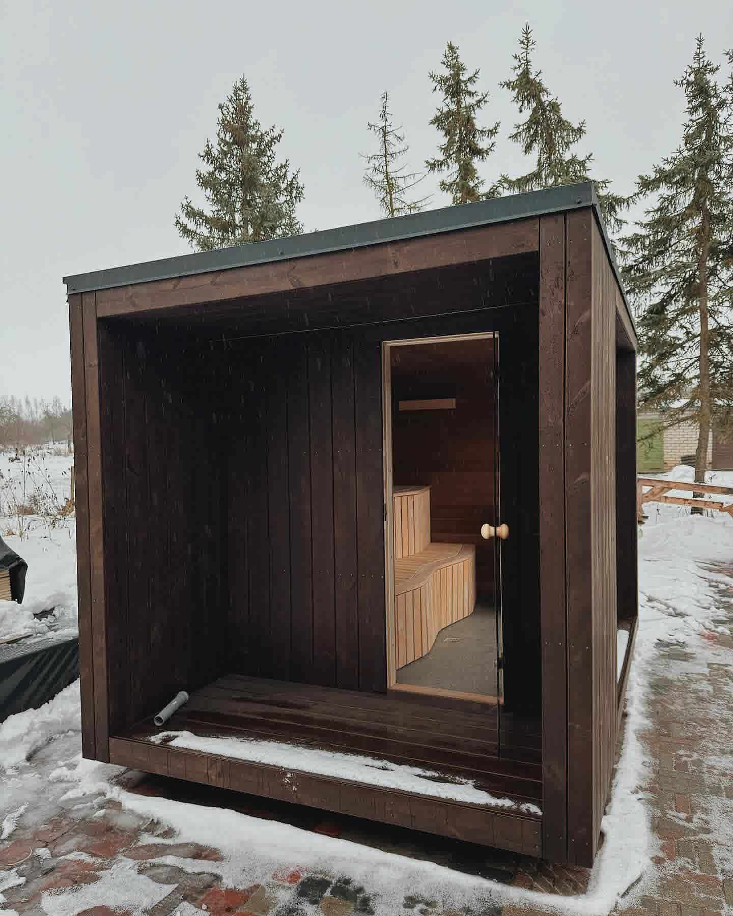 Handcrafted outdoor cube sauna with glass door showing the warm timber interior and tiered seating.